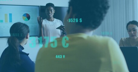 Presenting leader in white top holding tablet, gesturing in office, laptop, screen charts, currency