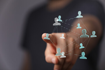 Close-up of a hand pointing at a digital network of human icons, symbolizing teamwork, communication, and connectivity.