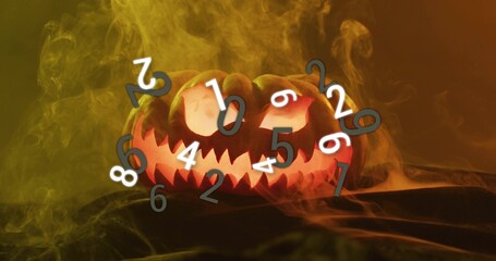 Glowing carved jack-o-lantern casting orange glow on dark cloth, with colored smoke and numerals
