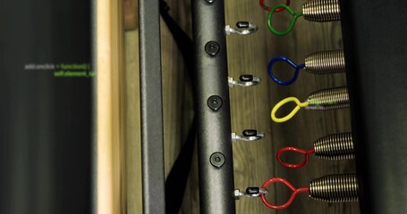 Focusing vertical metal rail with coil springs and color loop handles on gym board, showing screws