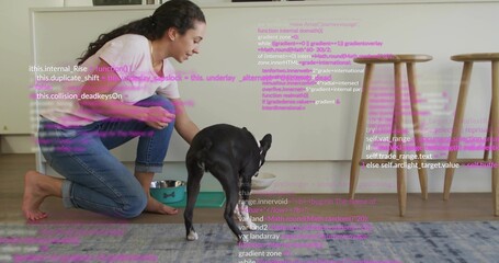Kneeling woman pink top, jeans reaching to black dog in kitchen with steel bowl, purple-pink code