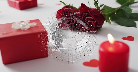 Fototapeta premium Displaying red rose lying on white tabletop, red gift box, lit candle, digital globe overlay
