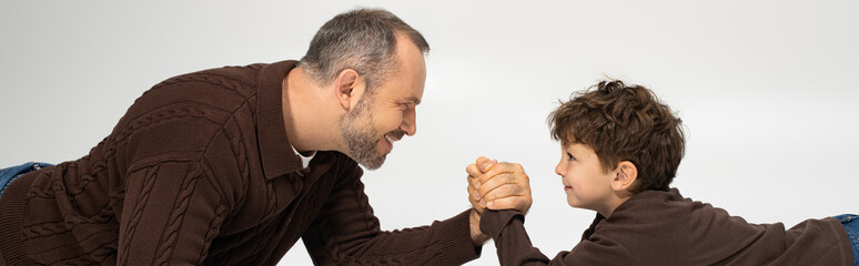 Joyful moments shared between a father and his young son during a playful arm wrestling match