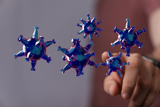 Conceptual image of hand interacting with digital virus models, symbolizing control or manipulation of disease - Powered by Adobe
