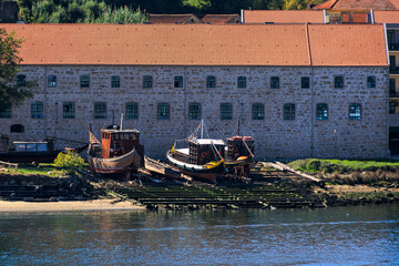 Traditional wooden boats resting on slipway beside historic stone warehouse along the Douro River, Portugal, Porto, 11 October 2025