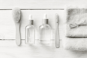 cleaning and skincare set on white wood backdrop in cloud dancer color scheme, towels folded, brushes and dropper bottles in a calm spa vibe, concept of beauty, spa, home care