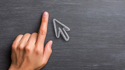 A hand points a finger to a chalk-drawn cursor on a textured, dark gray surface