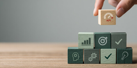 Hand Stacking Wooden Blocks with KPI Icon Above Business Strategy Symbols Representing Key Performance Indicators, Analytics, and Goal Achievement Concept