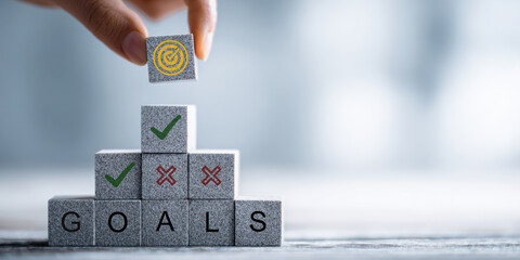 Hand Stacking Wooden Blocks with Target Icon Above Word GOALS Representing Achievement, Success, and Business Objective Concept