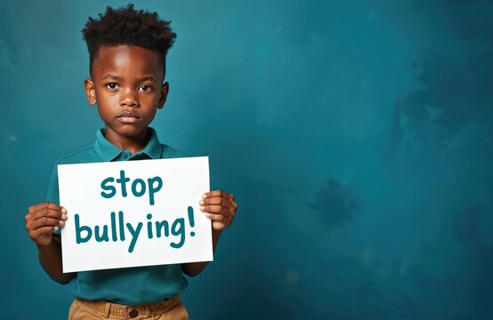 Young african american boy holds sign asking to stop bullying. Child expresses sadness, advocates for peace, speaks against harassment. Kid demands end to violence, needs support, seeks attention to - Powered by Adobe