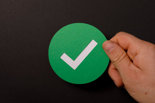 A hand holds a green checkmark icon, representing a positive concept. Perfect for success, approval, and decis