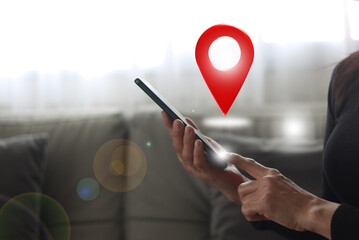 Close-up of a woman's hands holding a smartphone with a globe icon and a location pin