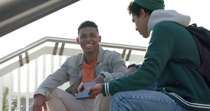 Lifting smartphone from pocket, Diverse male friends sharing laughter viewing screen on bleachers