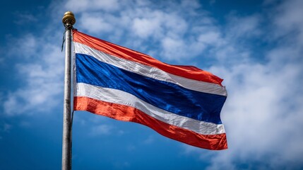Close-up of a flag with stripes of red, white, and blue against a bright, cloudy sky