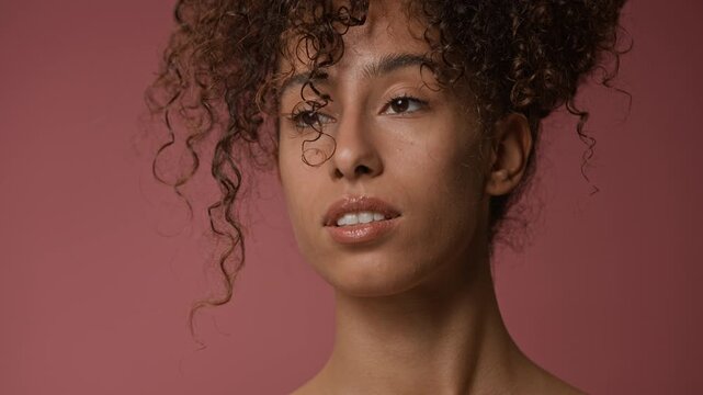 Push in shot of delicate young adult woman with glowing skin and no makeup looking around while posing for camera