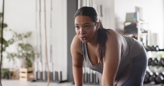 Upon steadying posture, woman wearing sportswear gripping hex dumbbell doing bent-over row in gym