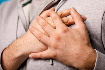 Fototapeta premium Close up of a person holding their chest, possibly experiencing pain, discomfort or anxiety. Medical concept w