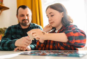 Father and daughter doing puzzle at home.
