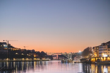 Fototapeta premium The evening light paints the city of Porto, Portugal as twilight settles. Gentle reflections ripple across the Douro River at dusk