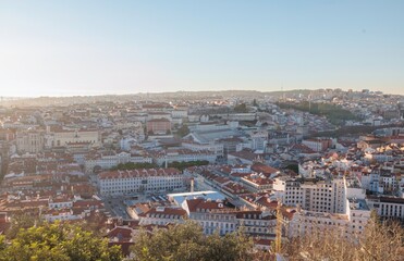 Fototapeta premium a captivating cityscape sprawls beneath a soft, golden sunlight, revealing a tapestry of buildings and streets in the vibrant city of Lisbon