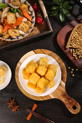 Delicious golden fried tofu puffs with Asian ingredients and soy beans on rustic wooden serving board
