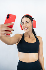 Healthy mexican woman taking selfie with headphones on white background