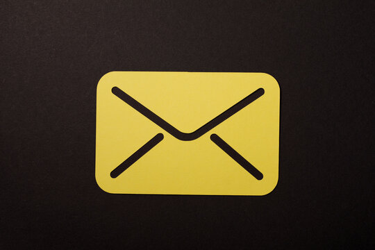 Close-up of a yellow envelope icon against a contrasting black background. Perfect for email, message, and com