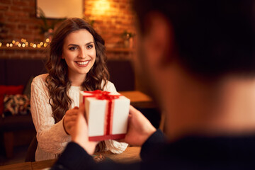 Couple giving Christmas gift during meeting at cafe