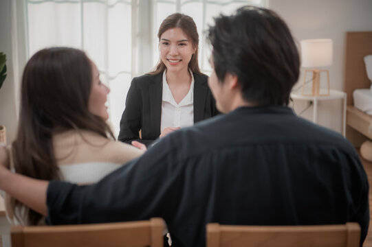 Asian financial consultant explaining new project investment to young couple in office. Real estate agent discussing mortgage options with family. Mortgage loan consultation.