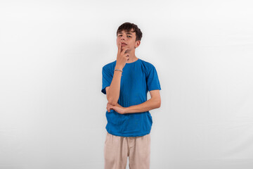 young casual dressed white male model teenager with hand on chin expression is pensive, pondering, considering or thinking about something. plain background studio setting