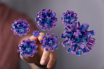 Conceptual image of virus cells held by a hand, symbolizing global pandemic, disease, and health crisis, digit