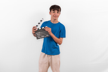 young happy casual dressed Generation Z influencer white male model teenage boy prepares to create and direct fun social media film reel with blank clapperboard slate. plain background studio setting