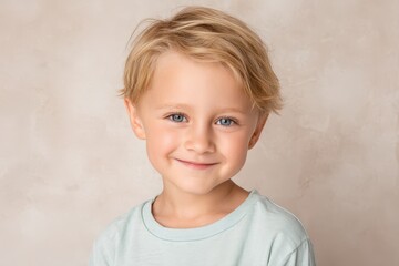 Naklejka premium Young light-haired boy with a warm smile looking at the lens in a sunny portrait