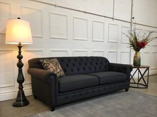 Modern living room with black sofa on cream wall background.
