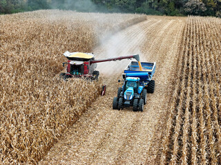 Aerial view of a combine offloading corn into a grain cart being pulled by a tractor