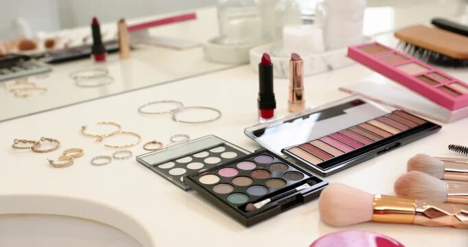Camera is panning right, revealing palettes, red lipstick and brushes on vanity, showing detail