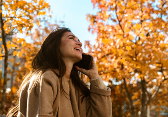 Woman talking on her smartphone in an autumn park