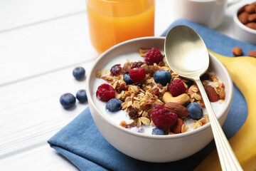 Healthy breakfast. Oatmeal with nuts, berries and milk on white wooden table, closeup. Space for text