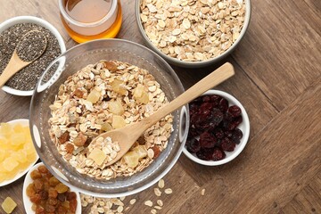 Making granola. Flat lay composition with oat flakes, dried fruits, chia seeds and honey on wooden table.