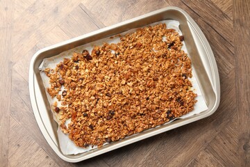 Tasty granola with dried fruits in tray on wooden table, top view