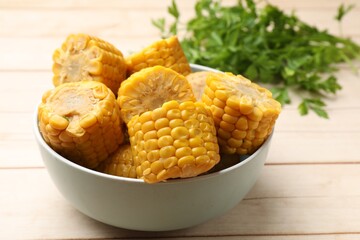 Pieces of tasty corn cobs and parsley on white wooden table, closeup