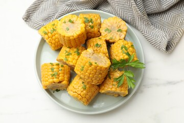 Pieces of tasty corn cobs with parsley on white table, top view