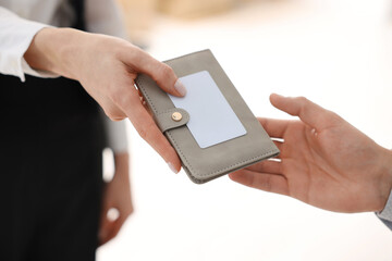 Receptionist giving passport and hotel key card to guest indoors, closeup
