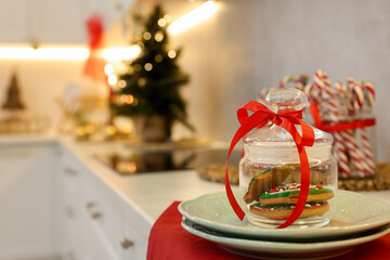 Christmas gingerbread cookies in glass jar, candy canes and festive decor on countertop in kitchen, selective focus. Space for text