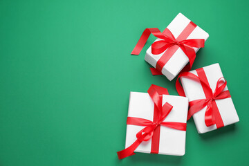 Wrapped Christmas gifts on green background, flat lay. Space for text