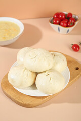 Handmade Pork Buns with Scallion Garnish and Cherry Tomatoes on Wooden Serving Board