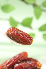 Golden dates fruit on wooden spoon with natural green background