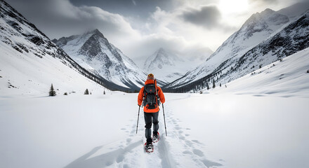 Adventurous hiker with snowshoes and backpack walks through vast snowy mountain landscape