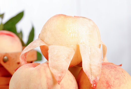 Fresh Yangshan Peach Slices with Decorative Peeled Skin Curls on White Background