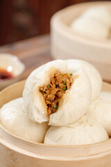 Fresh handmade steamed pork buns with scallions in traditional bamboo steamer - Asian cuisine